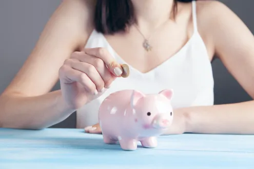 Woman putting change into a piggy bank